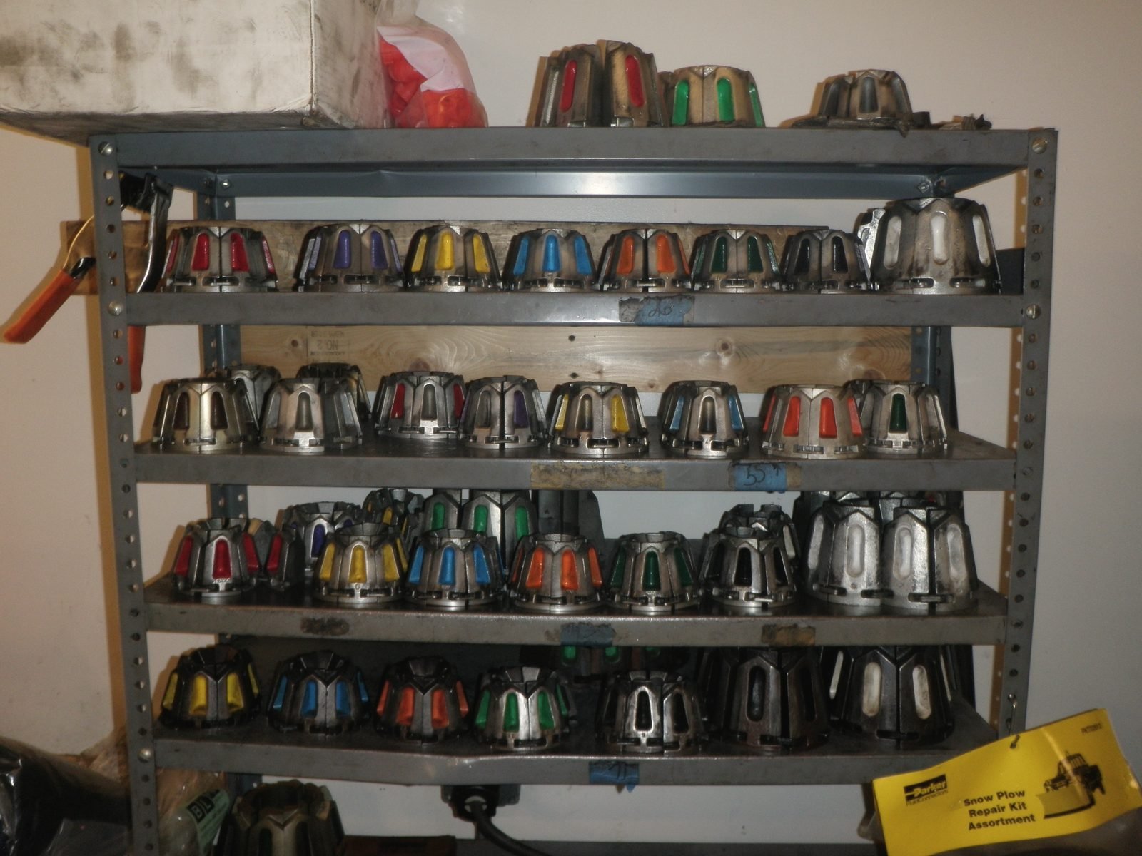A steel shelf holding rows of colour-coded hose crimp dies