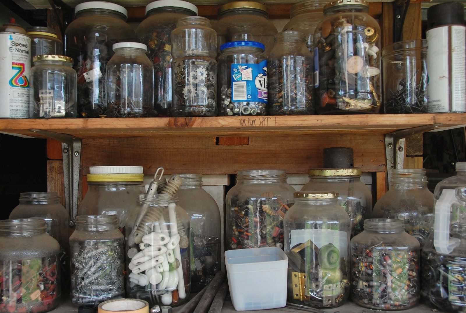 Shelves of glass jars filled with small fasteners in a workshop