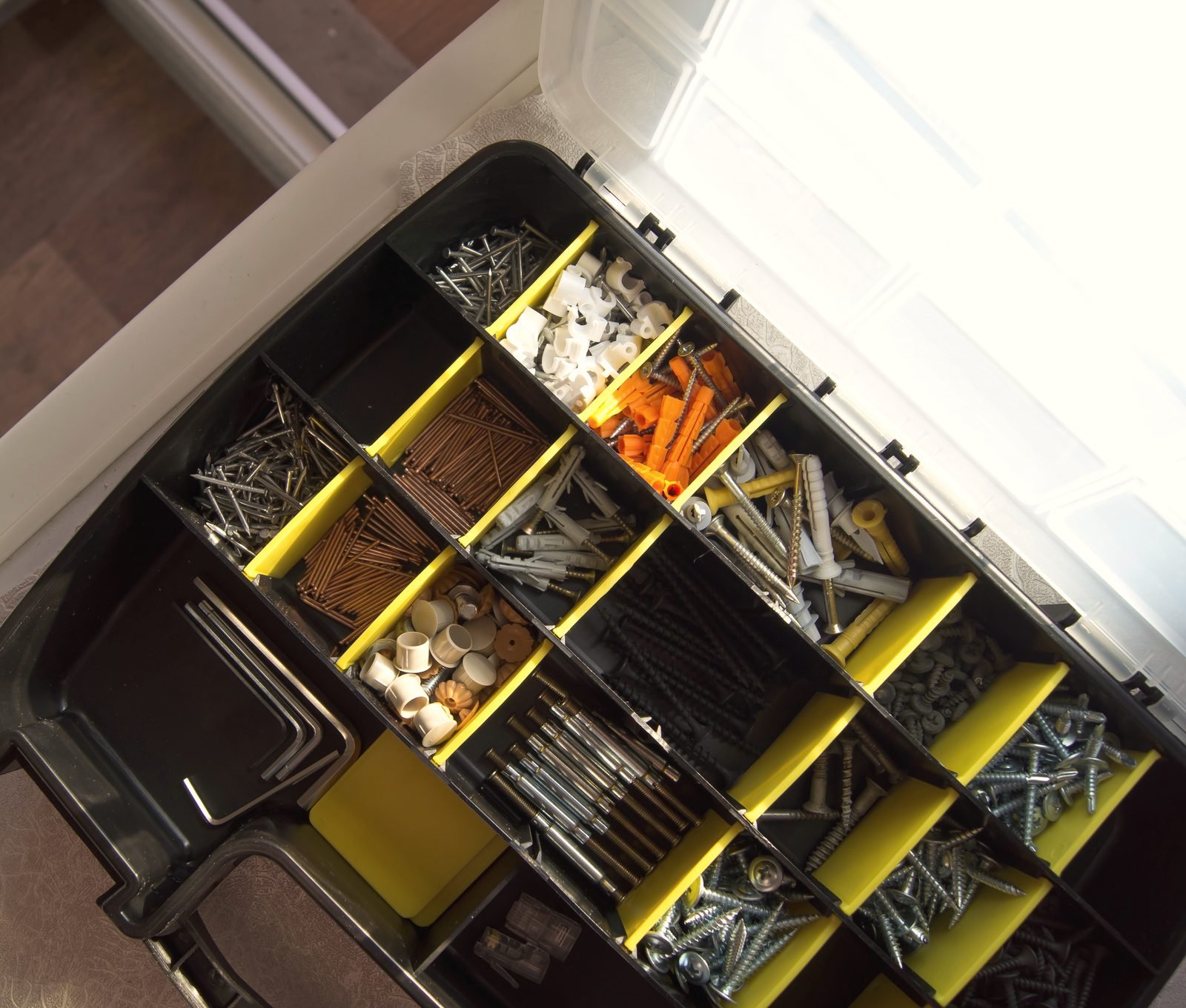 An open organizer case with compartments of screws and wall anchors